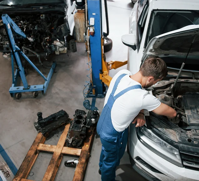 Un mécanicien inspecte le moteur d’une voiture dans un atelier automobile moderne.